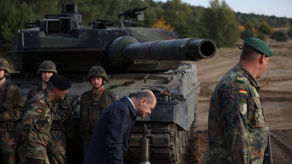 German Chancellor Olaf Scholz (C) lowers his head as he walks past a Leopard 2 main battle tank of the German armed forces Bundeswehr during a visit of German Bundeswehr's troops during a training exercise at the military ground in Ostenholz, northern Germany, on October 17, 2022. (Photo by Ronny HARTMANN / AFP)