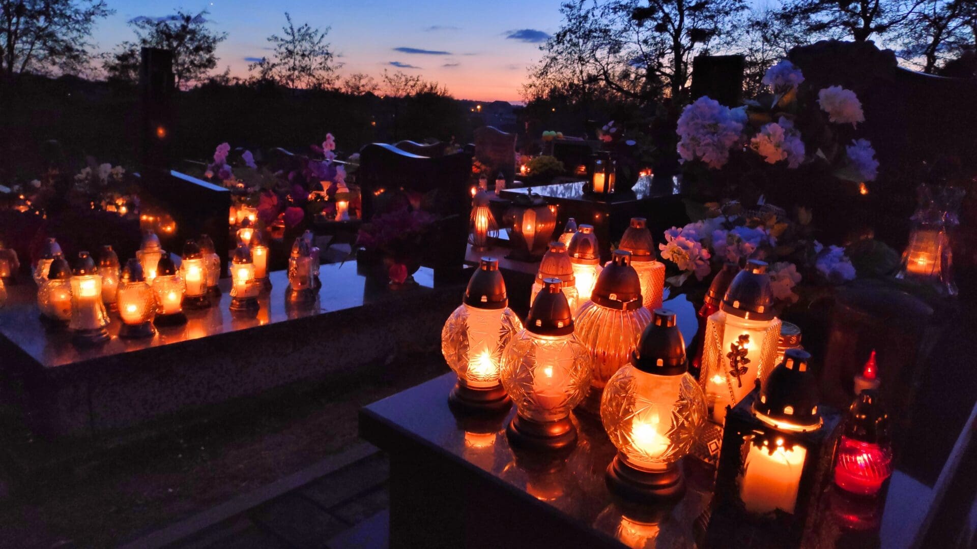 Candles lit on graves in a cemetery in Poland on All Saints Day.