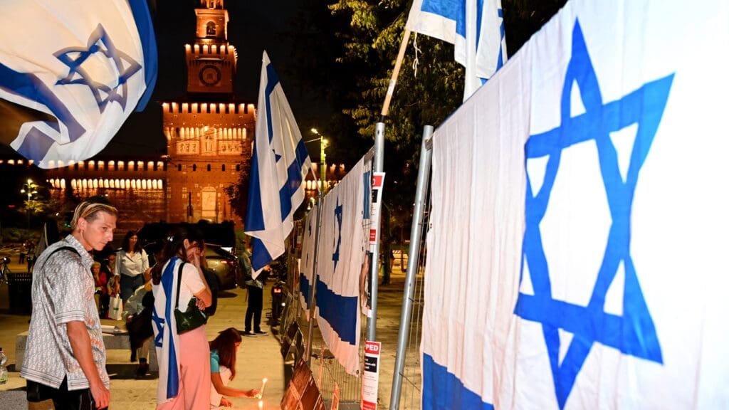 Demonstrators gather in front of Israeli national flags to pay tribute to victims during a rally in support of Israel in Milan on 12 October 2023.