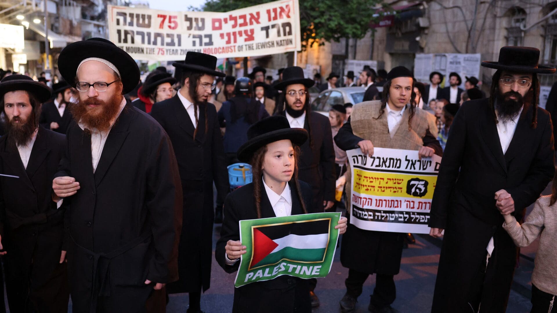 A boy holds a Palestinian sign as members of the Neturei Karta, an international organization of anti-Zionist Orthodox Jews, protest against the State of Israel on 26 April 2023.
