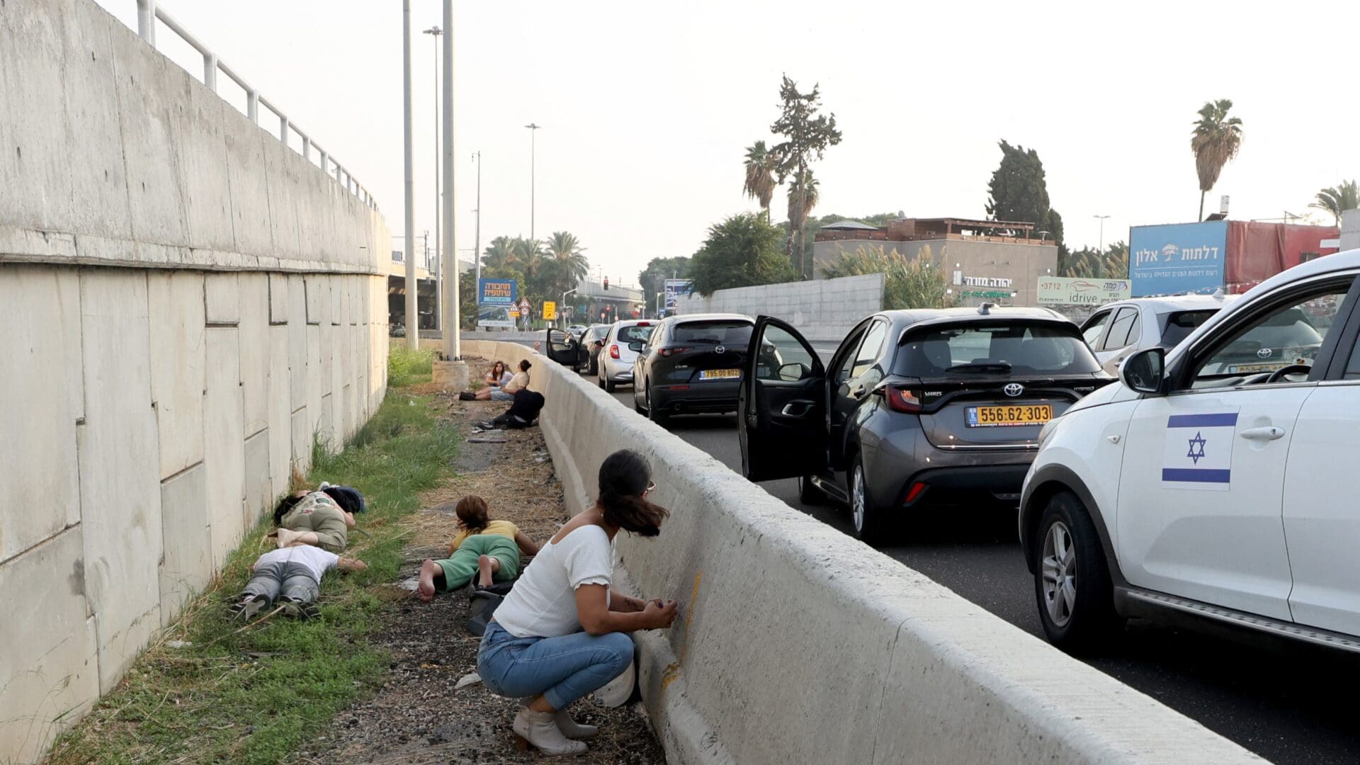 People leave their vehicles to take cover during a rocket attack from the Palestinian Gaza Strip along a main road in Tel Aviv on 24 October 2023.