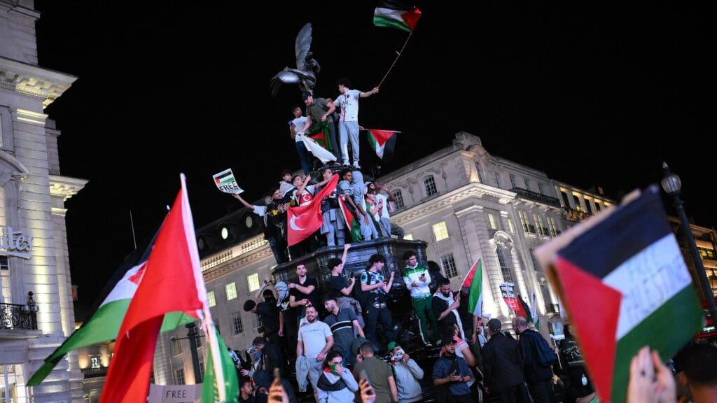 Pro-Palestine supporters wave flags and hold placards as they demonstrate at Piccadilly Circus in London on October 9, 2023.