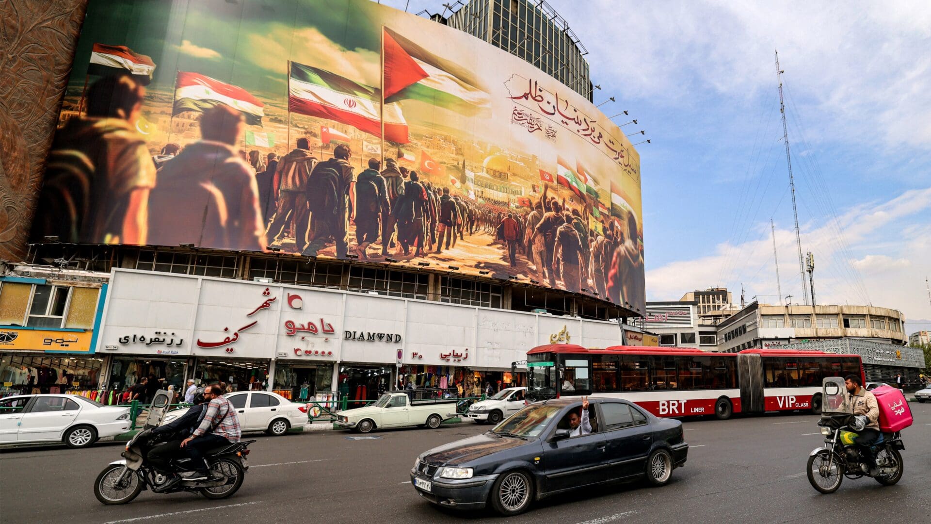 A motorist in Tehran gestures while driving past a giant billboard depicting Muslim peoples walking with their national flags towards the Dome of the Rock shrine in Jerusalem on 25 October 2023.