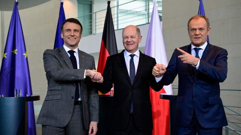 (L-R) French President Emmanuel Macron, German Chancellor Olaf Scholz and Polish Prime Minister Donald Tusk join hands at a press conference at the Chancellery in Berlin on 15 March 2024.