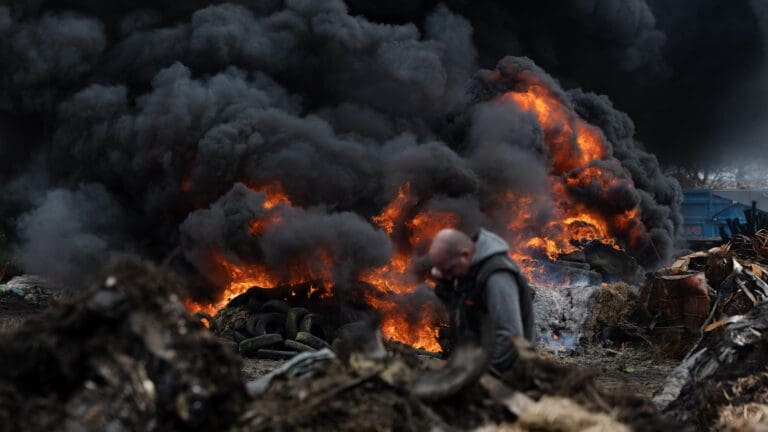 A farmer stands near a fire as farmer gather as part of the nationwide protests against agricultural policies in Plouisy, Western France on 20 February 2024.