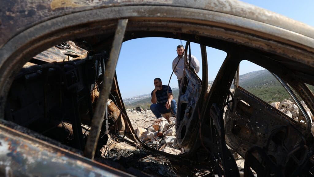 Palestinian men look at a burnt out car near Salfit in the West Bank after a group of Jewish settlers attacked a Palestinian village, killing one person and injuring three, and setting a house and a car on fire.