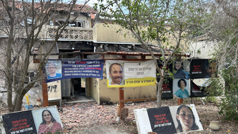 Portraits of victims in front of a house destroyed by terrorists in Kibbutz Be’eri PHOTO: Tamás Maráczi