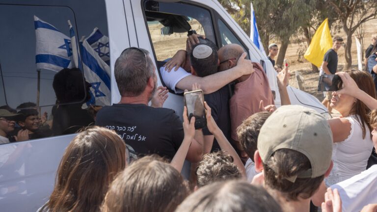 Former Israeli-Hungarian hostage Omri Miran (C) is welcomed by the crowd as he arrives in a van at his family's temporary home in Kramim kibbutz, in southern Israel, on October 17, 2025.