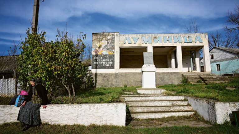 A woman rests beside the abandoned library ‘Luminita’ (The Glim), its name written in Cyrillic letters, in the village of Cimișeni, Moldova, 12 November 2023